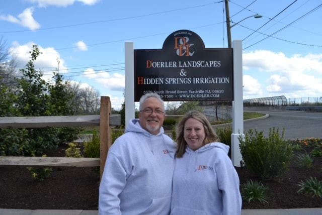 Gary Mozingo and his wife in front of the Doerler Landscapes & Hidden Springs Irrigation sign in Yardville, NJ
